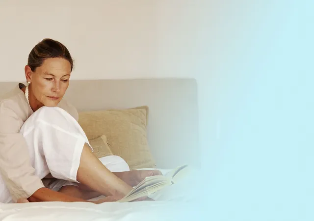 Woman reading a book on a bed