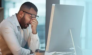 Man yawns at his desk